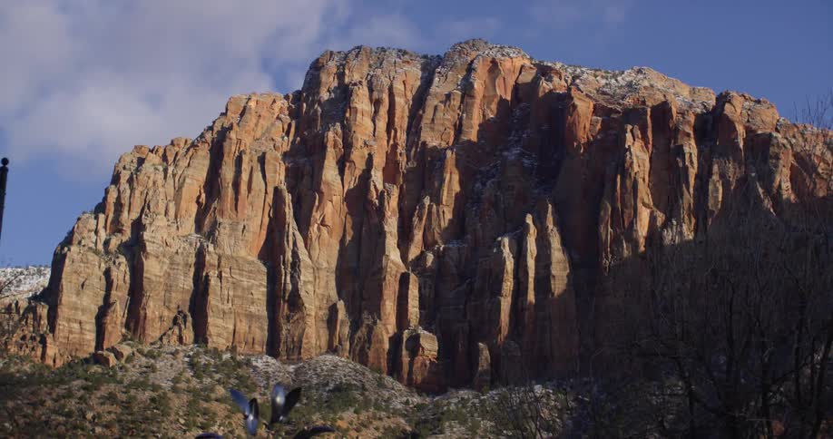 Steep face of a mountain under a blue sky