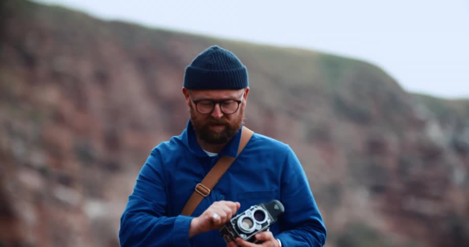 A man photographs using a vintage camera with red rock canyon walls behind him