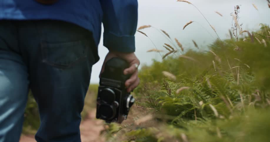 A man holding a camera is walking outdoors