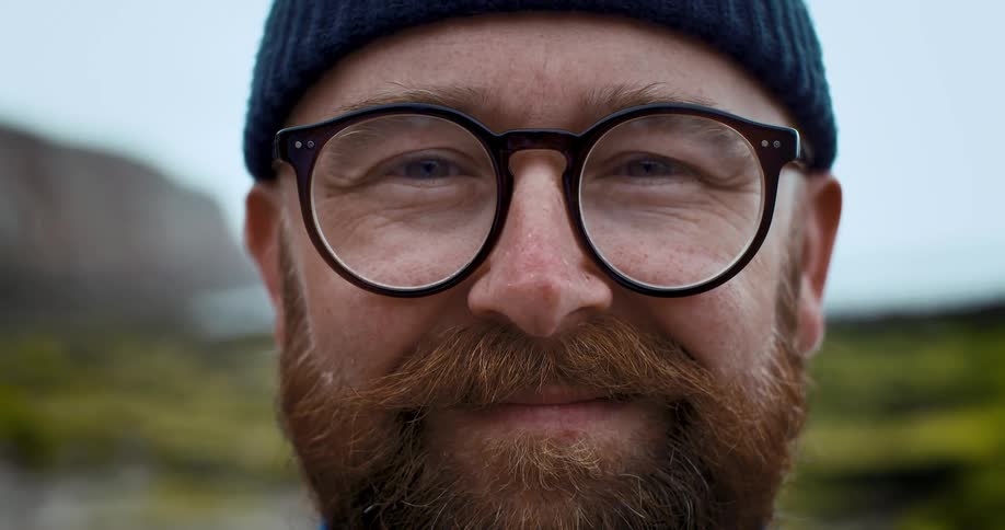 Close up of a bearded mans face wearing glasses