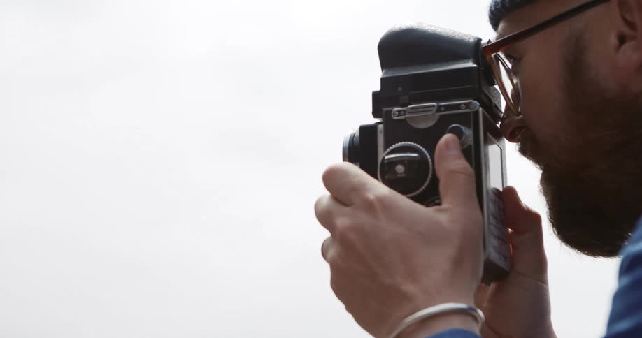 A man with a hat and glasses taking pictures with a camera