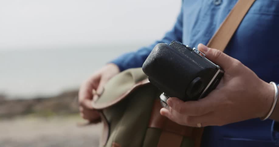 A person takes a camera out of a camera bag and twists a knob on it