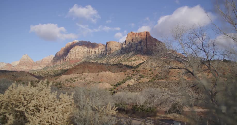 Small bushes grow on the slope of a tall and wide mesa