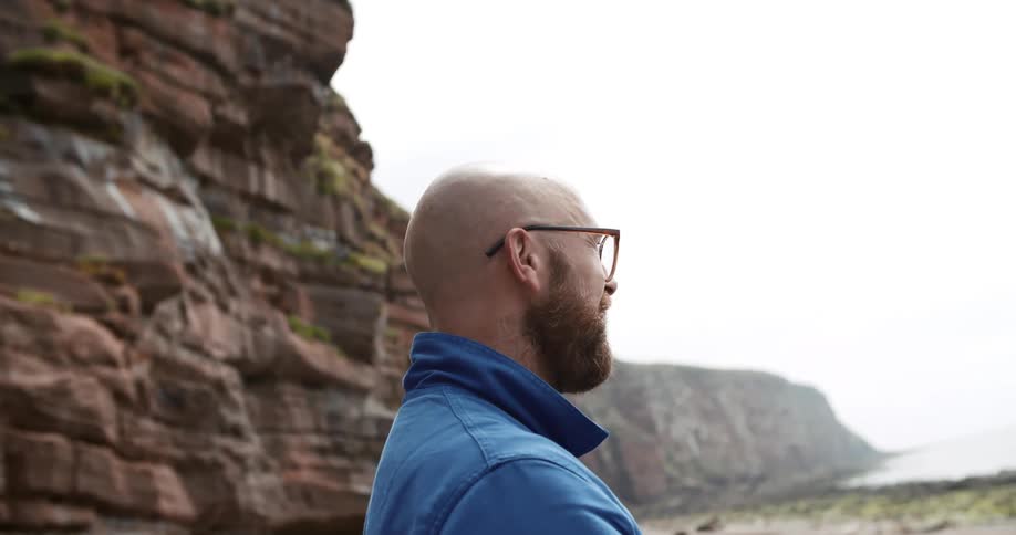 A man is standing outdoors by a cliff