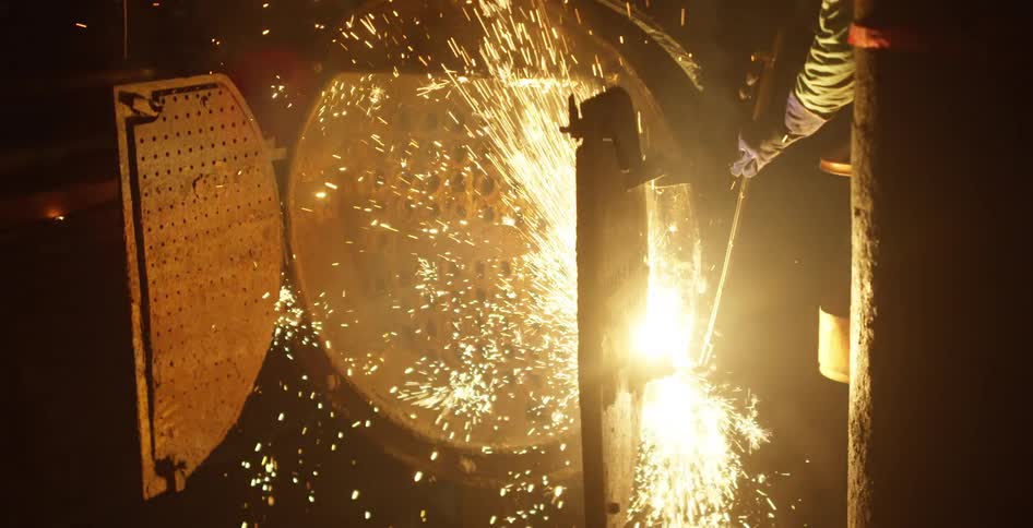 A welder is using a torch to fix a metal door