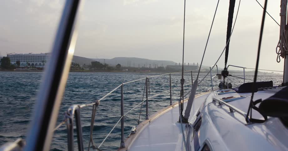 A sailboat travels toward land on a cloudy day
