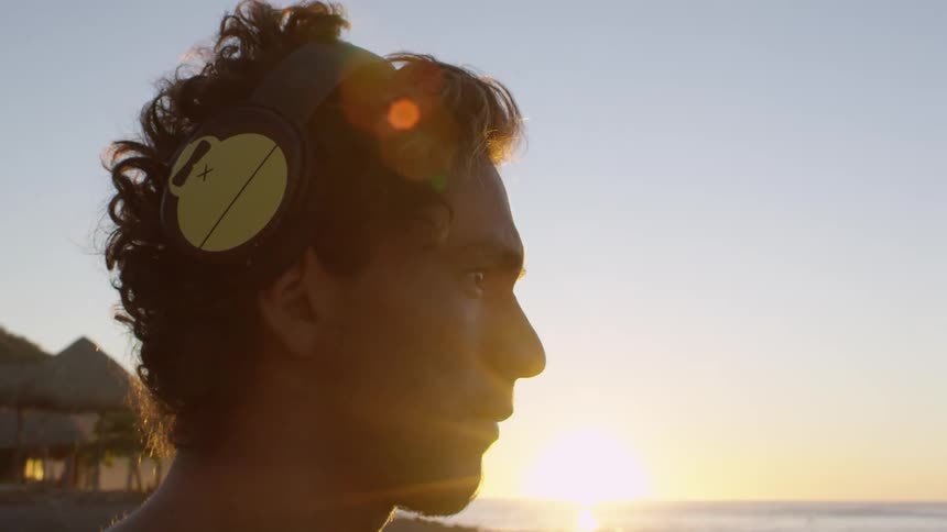 Man standing on the beach watches the sea at sunset