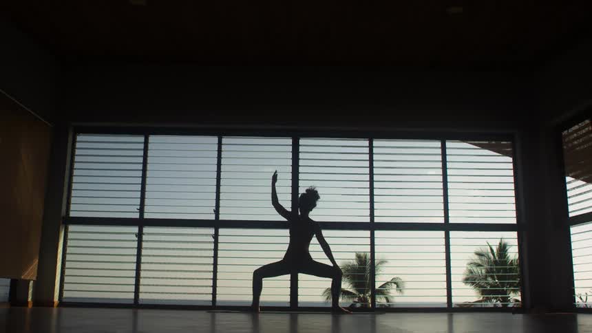 A woman does yoga in a mostly empty room in a house