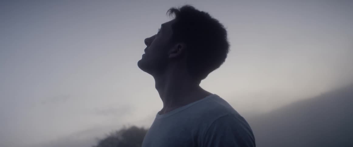 A man stands and looks up at the sky at dawn or dusk