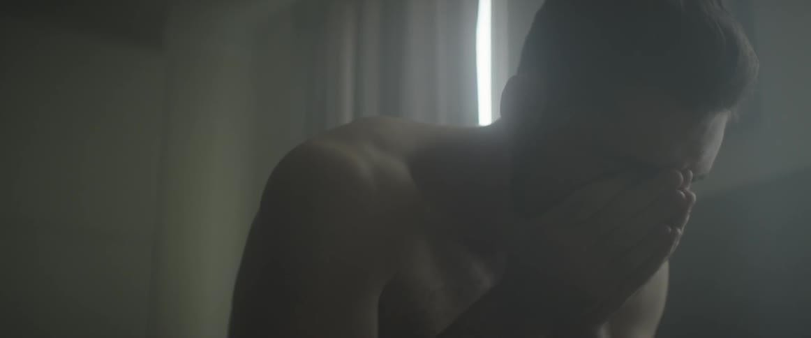 A man has his head in his hands by a window