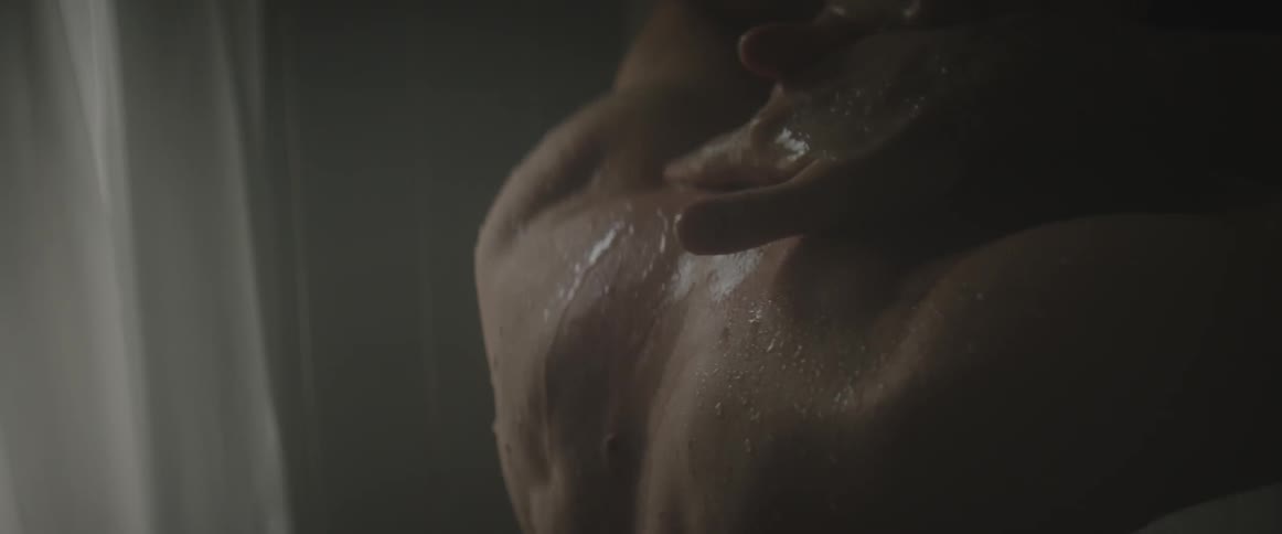 A man rubs his neck in the shower