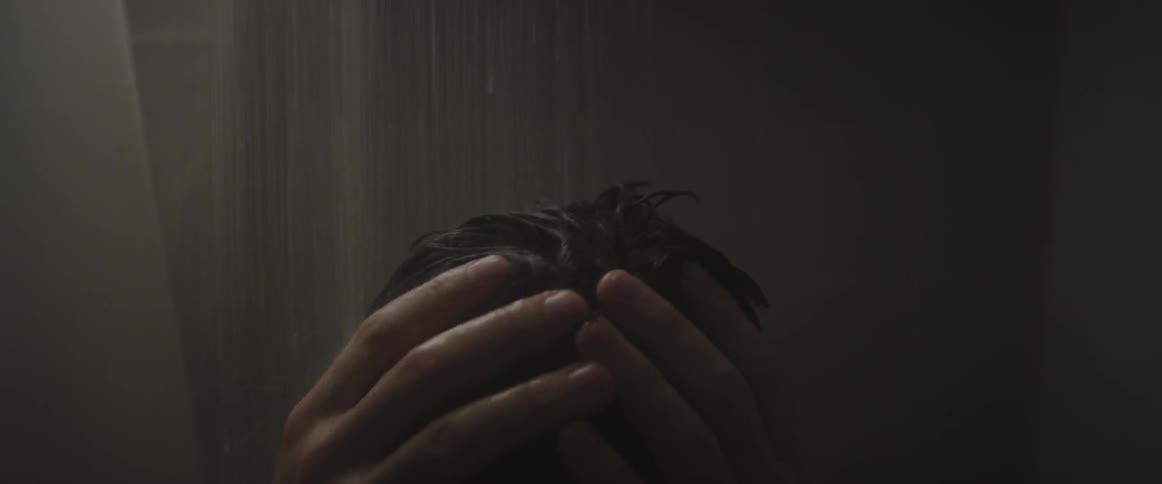 A man stands under a shower stream