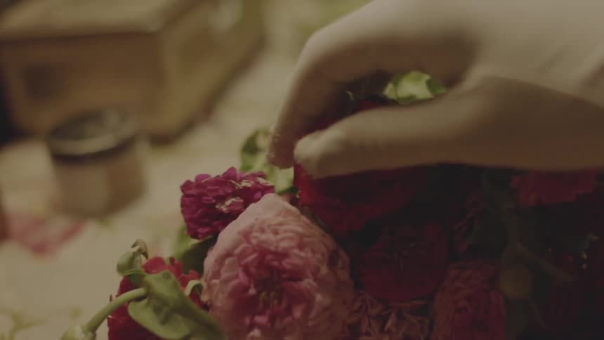 A gloved hand caresses a bouquet of flowers