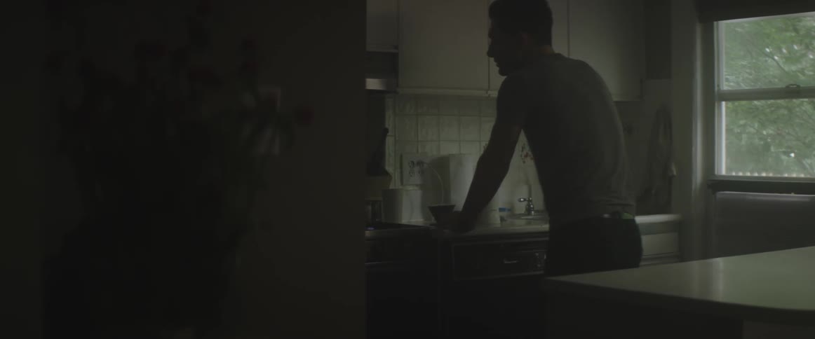 Angry man standing in a dark kitchen hits a cupboard