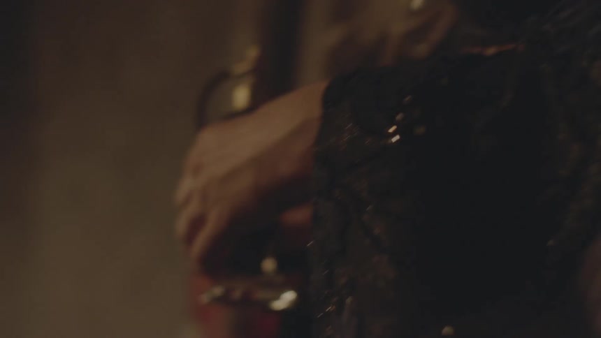 A woman in black holds a perfume bottle