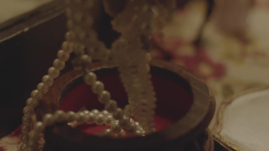 Hands fondle a string of pearls