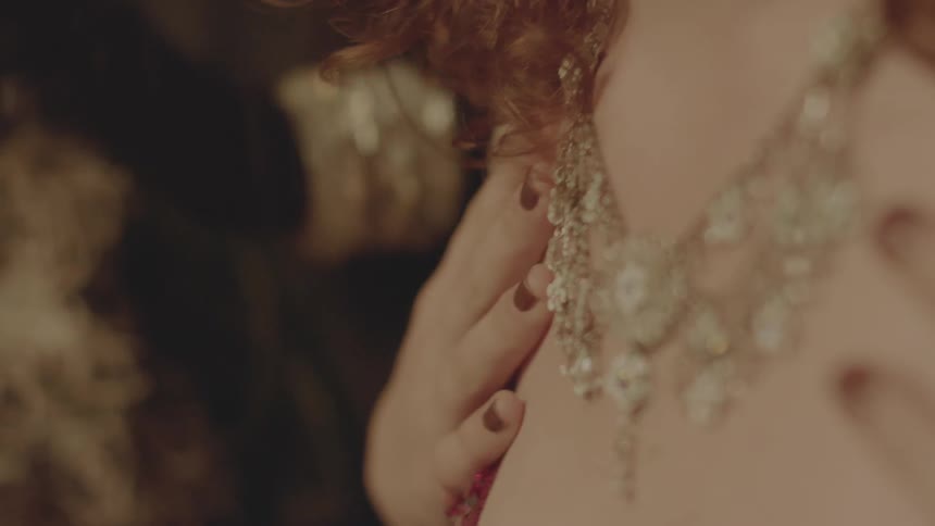 A woman touches her chest displaying a necklace