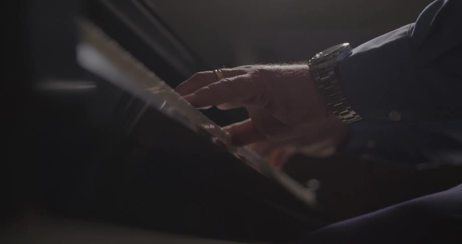 An older man's hands playing a piano