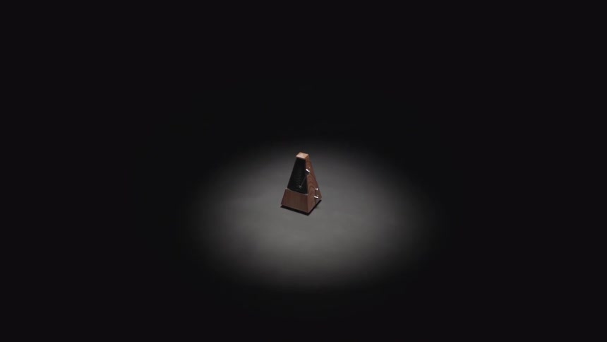 A stopped metronome sitting in a spotlight amid darkness