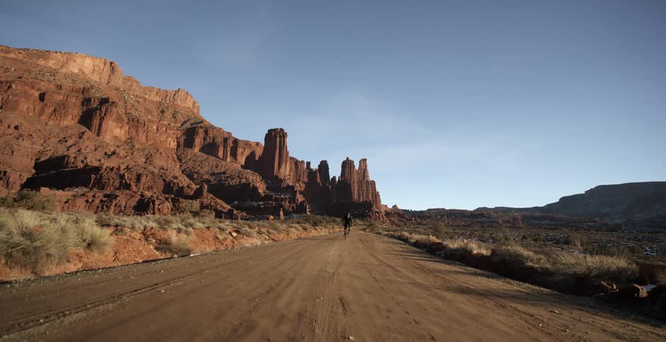 A person is biking on a dirt road