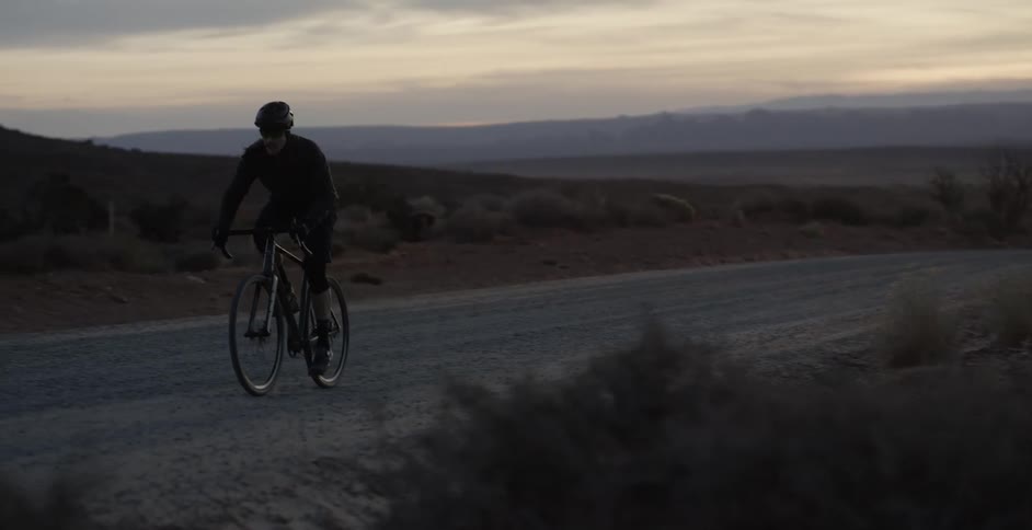 Silhouette of a road cyclist along a dirt road at dusk in Monument Valley