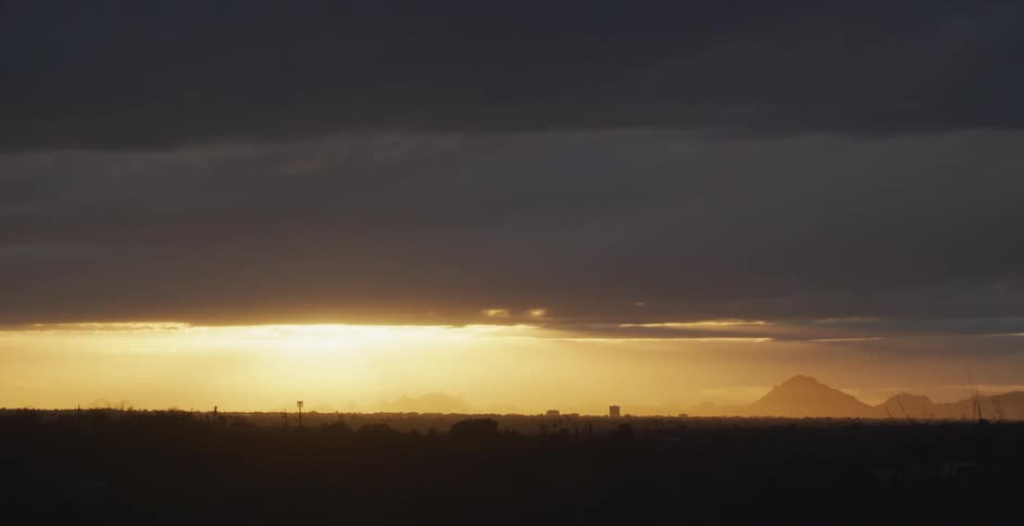 The sun peeks out of dense clouds on the horizon