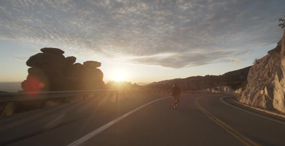 A man cycles on a street past canyons