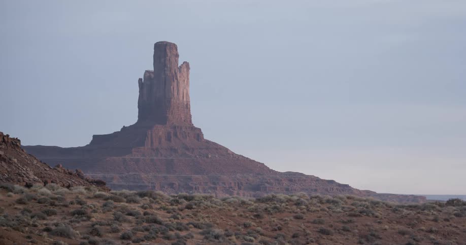 An enormous rock formation rises from a desert
