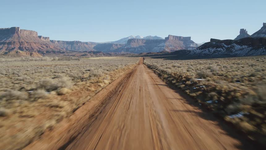 A long dirt road stretches to a distant mountain range