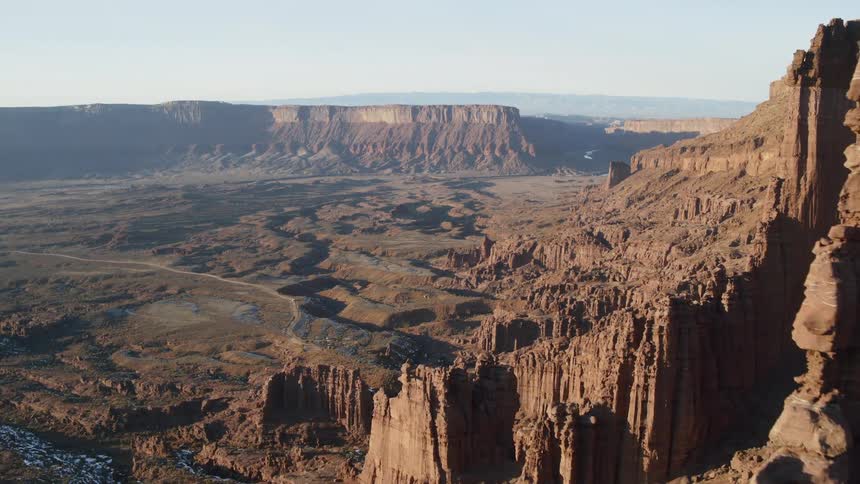 Rivers occupy rough terrain between mesa under a hazy sky