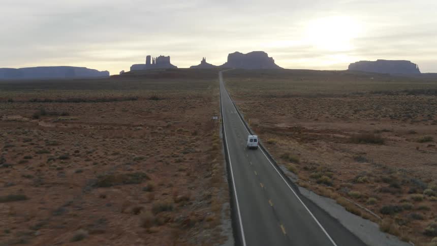 The vehicle travels down the road in Monument Valley