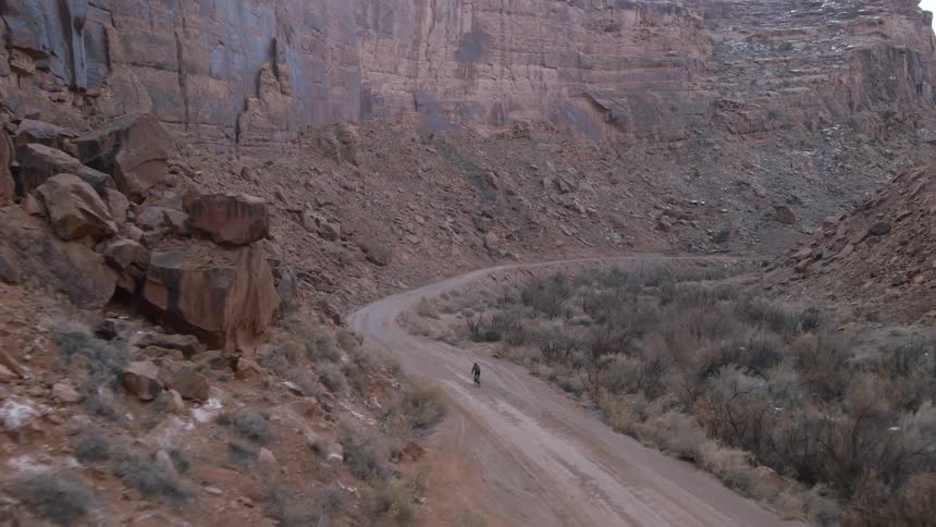 A person cycles past a large canyon