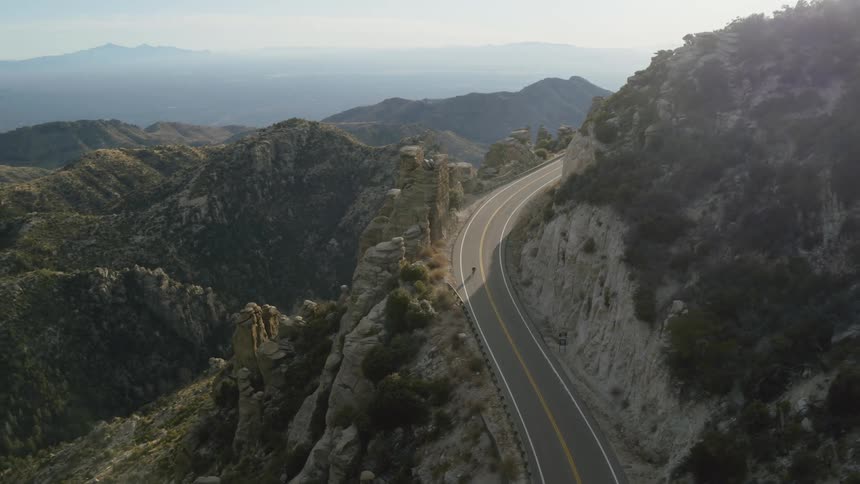 Aerial view of a cyclist cycling down on a mountain road