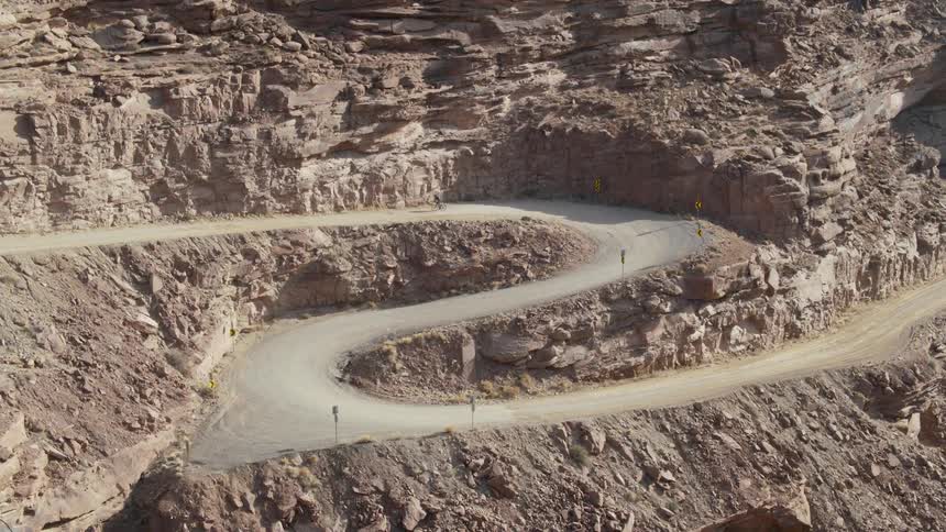 A cyclist climbing a curvy road on a mountain in a canyon