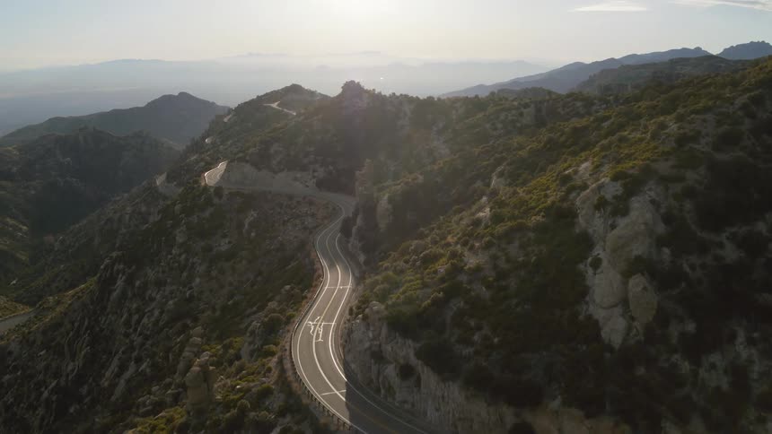 A highway curves through the mountain side near a steep slope