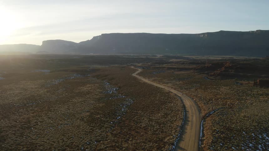 Aerial view of cyclist riding road bike on long desert road at sunset