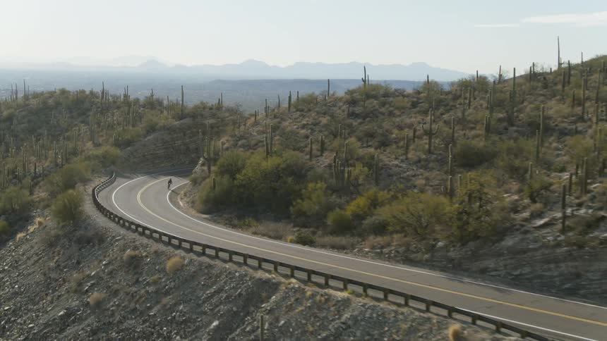Aerial view of a cyclist cycling down a mountain highway