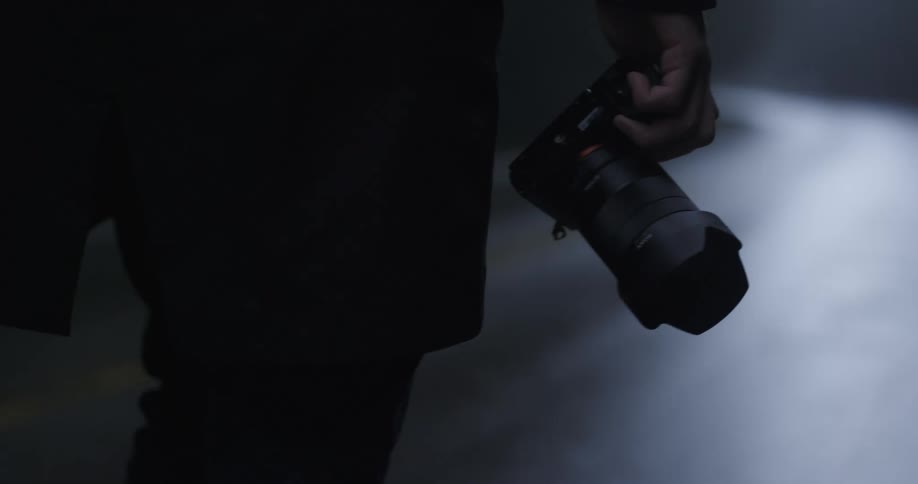 A person carrying a camera walks