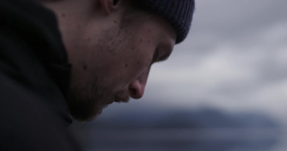 A man is standing outdoors while wearing a hat
