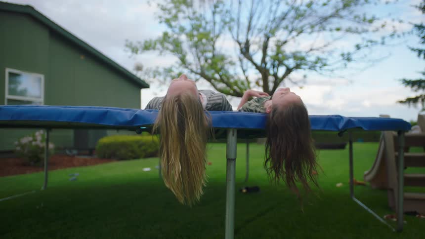 Two girls lie on a trampoline and talk
