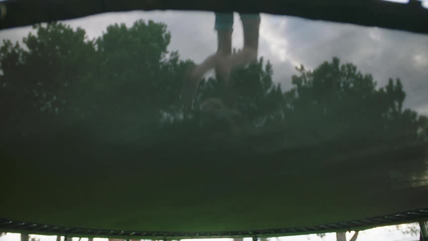 Two girls jump on a trampoline outside