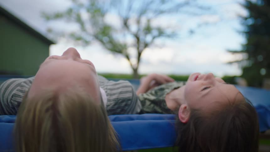 Two girls lie on a trampoline and laugh