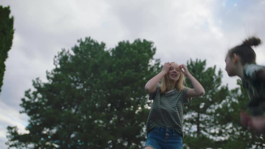 Two girls jump on a trampoline