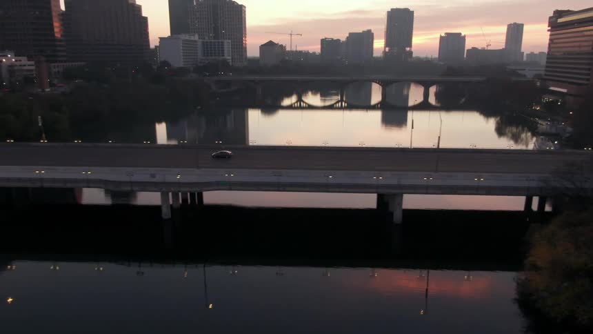 Aerial view of a car crossing the bridge at sunset