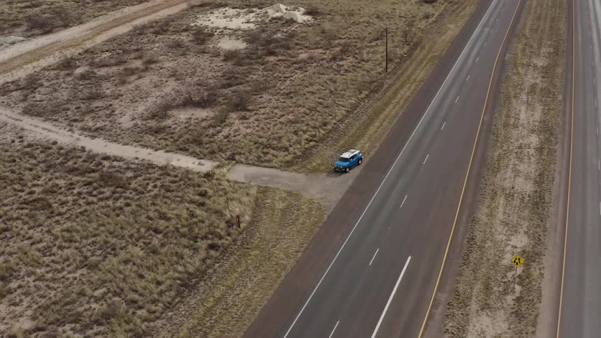A vehicle pulls off of the highway and over to a dirt road