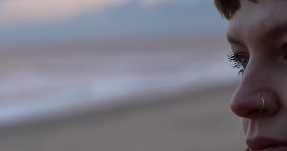 Woman looks ahead in the field at dusk