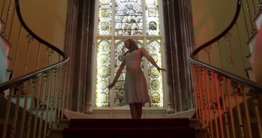 A young woman dances at the top of some stairs