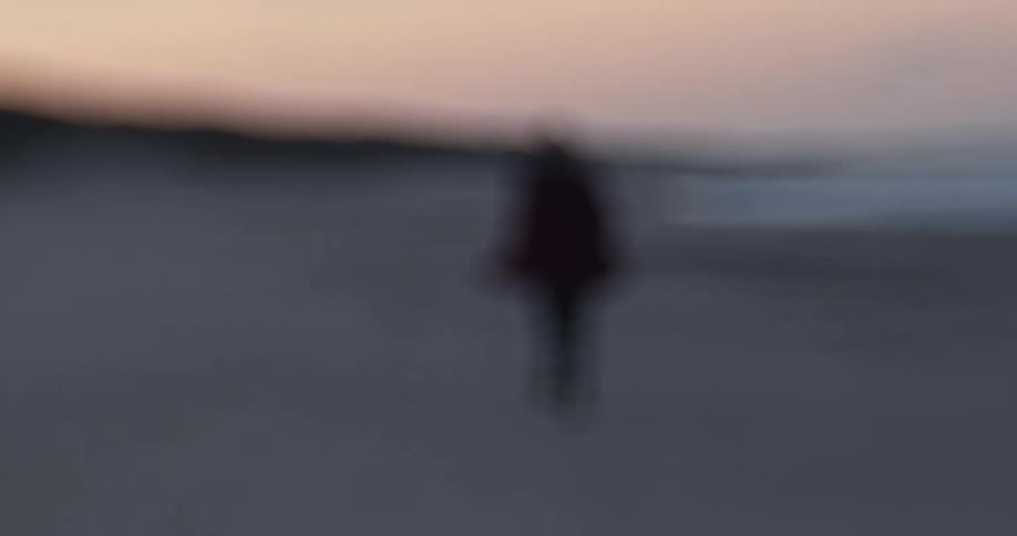Woman runs on the beach at dusk next to the sea