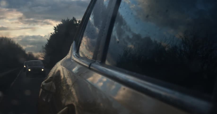 A car travels down a road at dusk