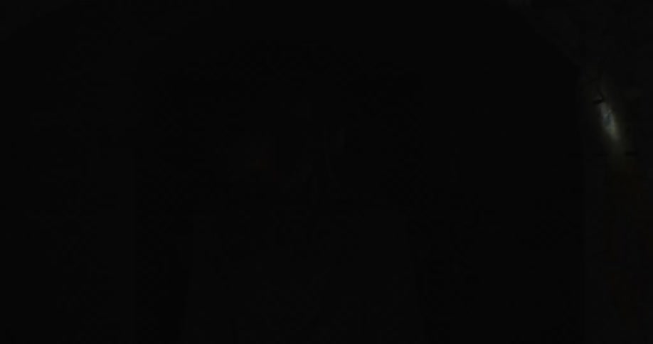A woman runs in to a dark tunnel with a torch